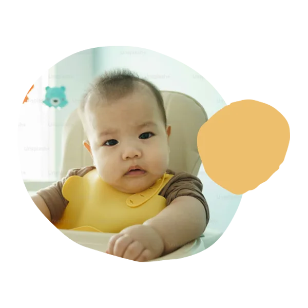 a baby sitting at a table wearing a bib