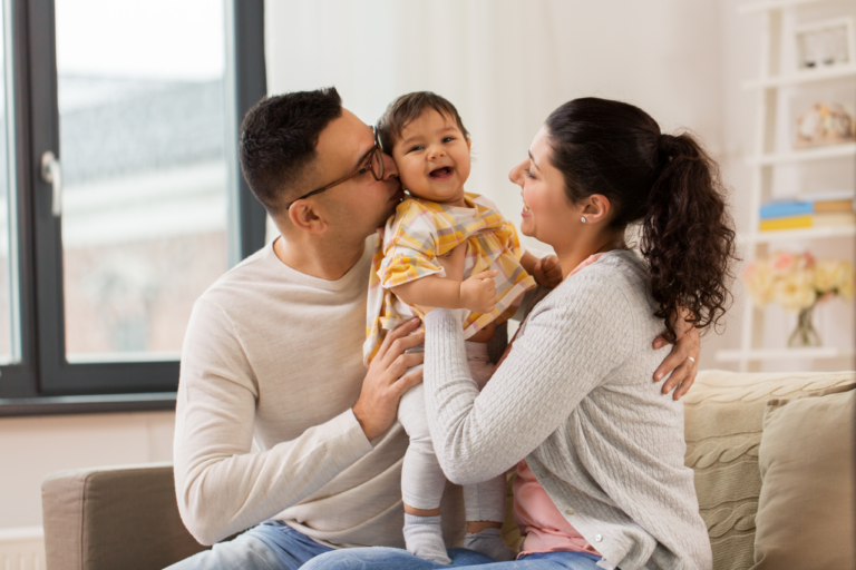 Two adults holding a smiling toddler