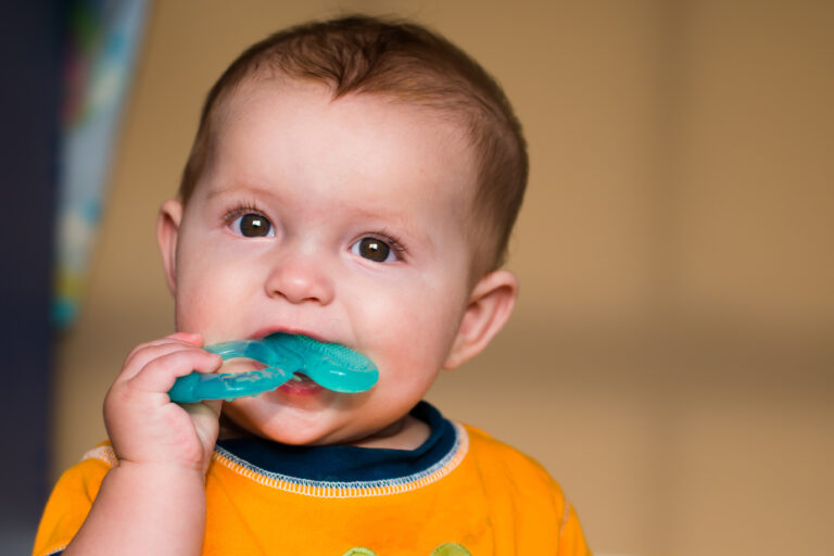 Baby chewing on teething ring toy
